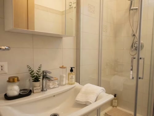Bagno moderno dell'appartamento A Casa di Imma Milano con vanity bianca, specchio, box doccia e servizi