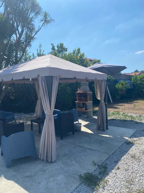 Área de refeições ao ar livre da Pousada Casa Augusta com gazebo branco, cadeiras estofadas e lareira de tijolos em Braga, Portugal