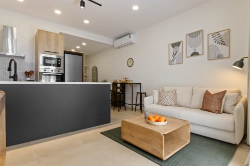 Modern Ayma Suite living room in Alhaurín de la Torre with cream sofa, wooden coffee table, and open-plan kitchen