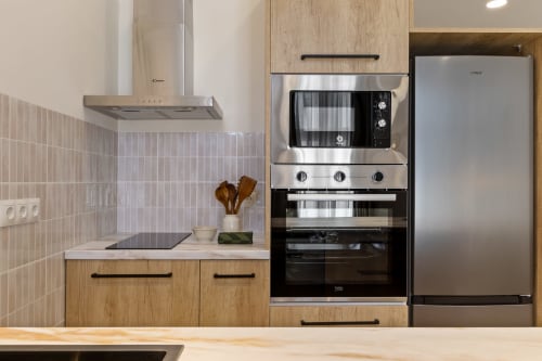 Modern kitchen in Ayma Suite apartment, Alhaurín de la Torre, with stainless steel appliances, wooden cabinetry, and tiled