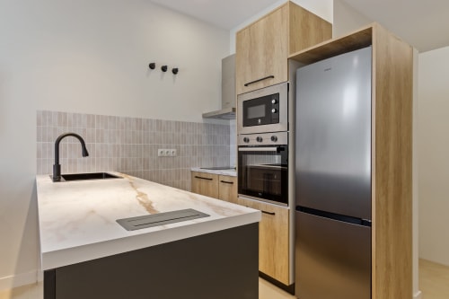 Modern kitchen in Ayma Suite apartment, Alhaurín de la Torre, with wooden cabinetry, stainless steel appliances, and marble