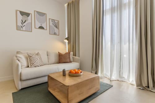 Modern living room in Ayma Suite apartment, Alhaurín de la Torre, with cream sofa, wooden coffee table, and mountain views