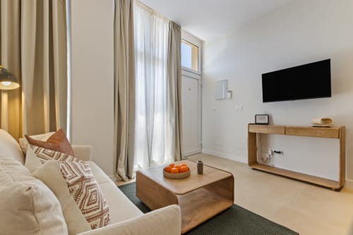 Modern apartment living room at Ayma Suite in Alhaurín de la Torre with cream sofa, wooden furniture, and wall-mounted TV