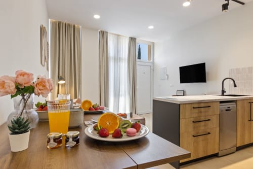 Modern kitchen-dining area in Ayma Suite with fresh fruit, orange juice, peony flowers, and mountain views in Alhaurín de la