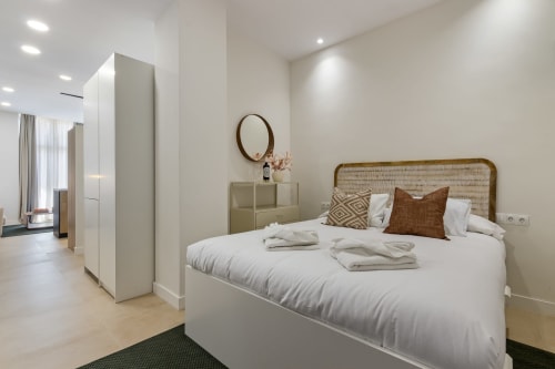 Modern Ayma Suite bedroom in Alhaurín de la Torre with rattan headboard, white bedding, and ensuite bathroom