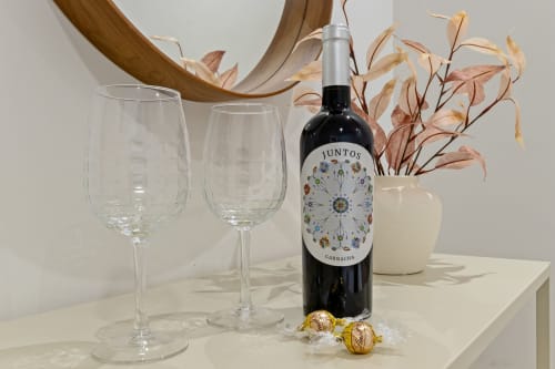Juntos Garnacha wine bottle with wine glasses and dried flowers in Ayma Suite at Alhaurín de la Torre