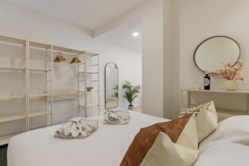 Ayma Suite bedroom with white bed, modern mirror, potted plant, and ensuite shower at Alhaurín de la Torre hotel
