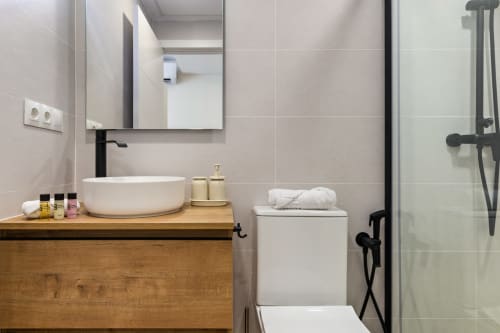 Modern bathroom at Ayma Suite in Alhaurín de la Torre with round sink, wooden vanity, and rain shower