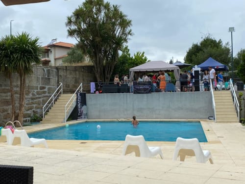 Piscina ao ar livre do hostel Casa Augusta com espreguiçadeiras brancas, tenda de eventos e hóspedes em Braga, Portugal