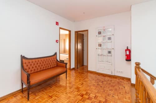 Corredor da pousada Sleep & Go em Esposende com sofá laranja, piso de madeira e equipamento de segurança contra incêndio