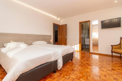 Quarto duplo padrão no hostel Sleep & Go em Esposende com duas camas, piso em parquet e comodidades modernas