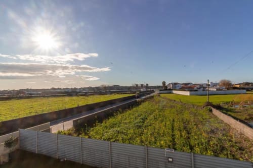 Vista da paisagem rural com campos verdes, canal e edifícios ao longe em Esposende, Portugal