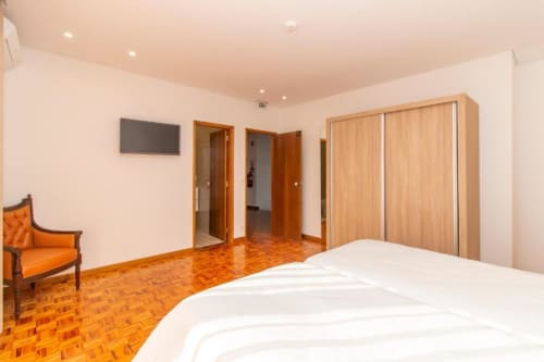 Quarto twin espaçoso no Sleep & Go hostel em Esposende, com piso de madeira, cama branca e comodidades modernas