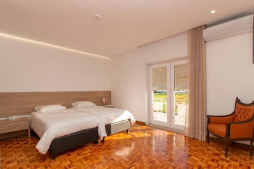 Quarto duplo standard no hostel Sleep & Go em Esposende com piso em madeira, camas twin e acesso à varanda