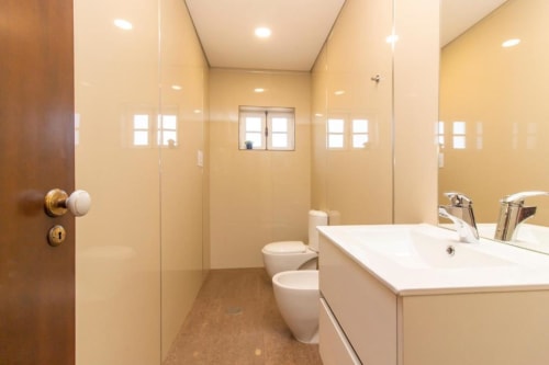 Banheiro compartilhado moderno no Sleep & Go hostel em Esposende com pia branca, sanitário e box de vidro
