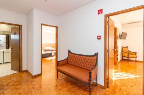 Corredor do hostel Sleep & Go em Esposende com piso de madeira, portas de quartos e banco estofado laranja