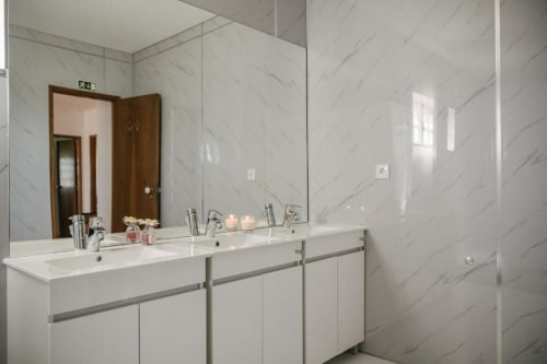 Banheiro compartilhado moderno no Sleep & Go hostel em Esposende com paredes em mármore, dupla pia e acabamentos contemporâneos