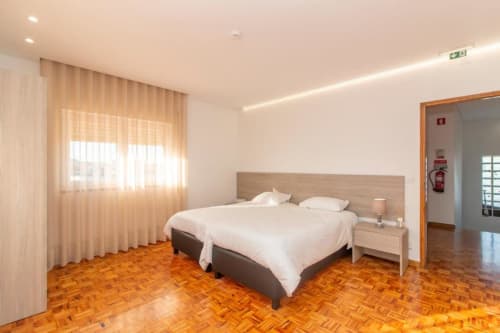 Hostel Sleep & Go em Esposende: quarto Twin Standard luminoso com piso de parquê, cama, criado e cortinas translúcidas