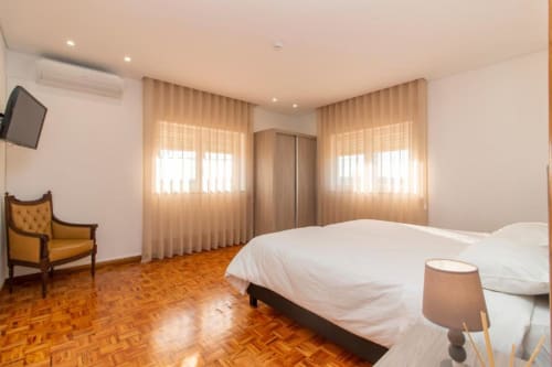 Quarto Twin Standard no hostel Sleep & Go em Esposende com camas individuais, piso de madeira e luz natural das cortinas translúcidas