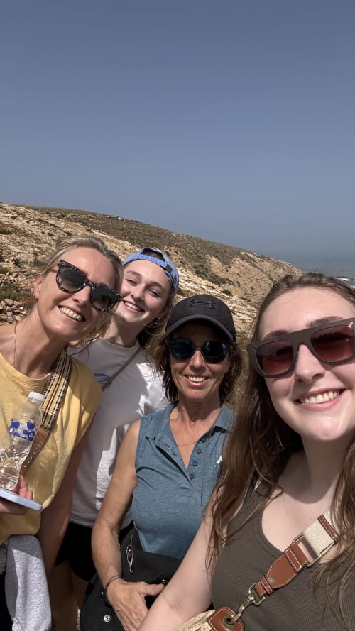 Quatre femmes souriantes à la maison d'hôtes Maison la Chèvre à Essaouira avec les collines du désert en arrière-plan
