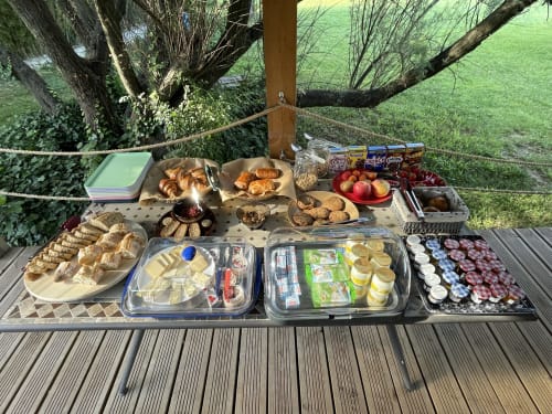 Petit-déjeuner en plein air aux Jardins Du Soleil à Avignon avec viennoiseries, charcuterie, fruits et pain frais