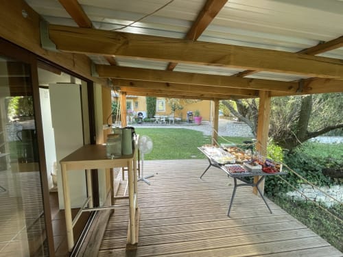 Terrasse couverte aménagée pour diner aux Jardins Du Soleil, gîte d'Avignon surplombant de verdoyants jardins