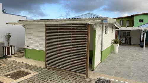 Bungalow Atoll à la Résidence B&L Lagon à Sainte-Luce, façade verte et blanche, volets métalliques ajourés et terrasse pavée