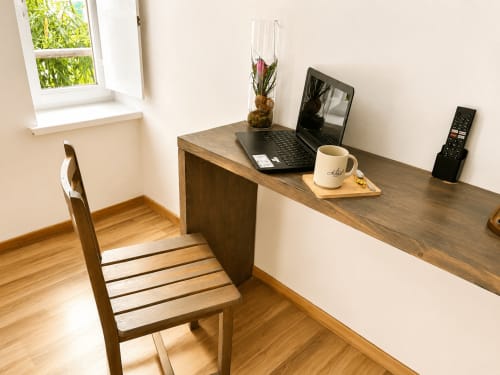 Bureau en bois avec ordinateur portable, tasse de café et fleurs à l'Au Bon Gîte B&B à Senones, France