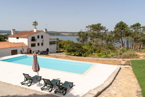 Apartamento à beira do lago com piscina, espreguiçadeiras e pinheiros com vista para o lago de Nadadouro em Portugal