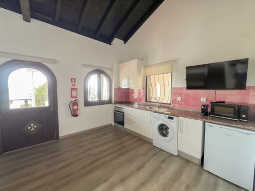 Cozinha moderna com eletrodomésticos brancos, azulejo rosa e vista para o lago no Alojamento Local Monte Horeb, Nadadouro