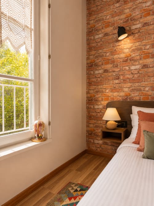 Chambre accueillante à Au Bon Gîte avec murs en briques apparentes, vue sur le jardin, parquet et ambiance chaleureuse à Senones