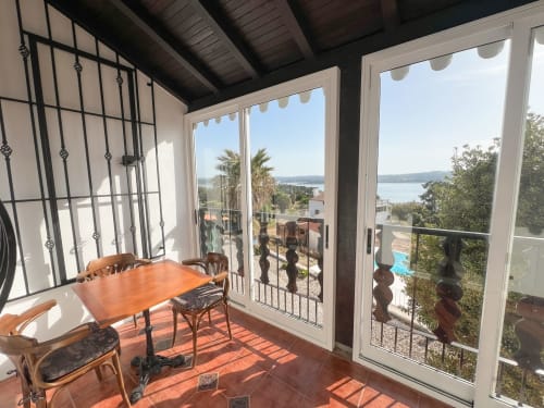Terraço ensolarado com mesa de jantar com vista para o lago Nadadouro no apartamento-hotel Monte Horeb