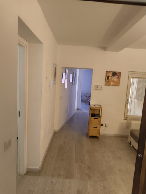 Bright hallway in Casa di Alfredo apartment in Siena with wooden floors, white walls, and doors to multiple rooms