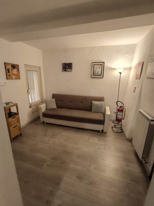 Bright living room in Casa di Alfredo apartment, Siena with brown sofa, wooden flooring, and modern amenities