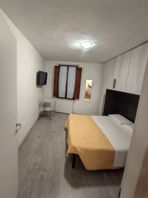 Modern bedroom at Casa di Alfredo B&B in Siena with bed, TV, wardrobe, and window