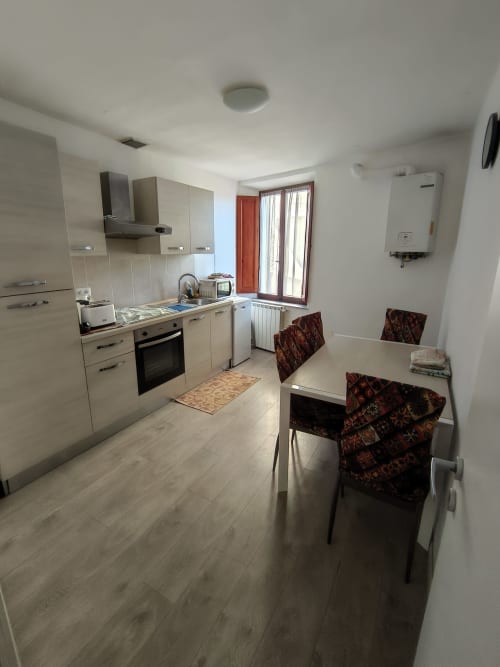 Modern kitchen and dining area in Alfredo's House apartment in Siena with cream cabinets, dining table, and window view