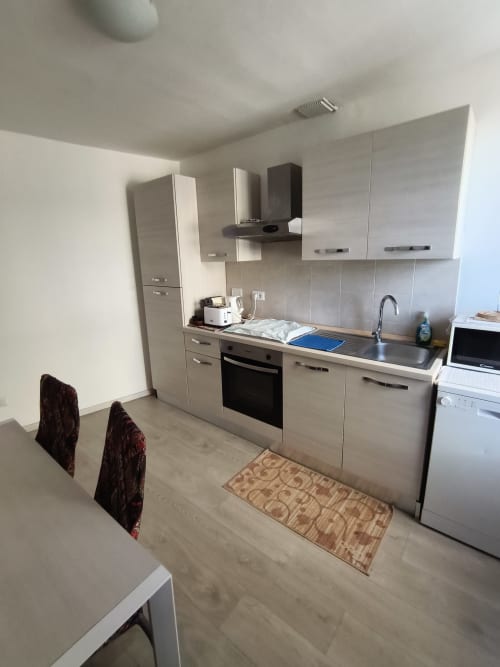 Modern kitchen in Casa di Alfredo apartment, Siena, with light cabinets, stainless steel appliances, and dining area