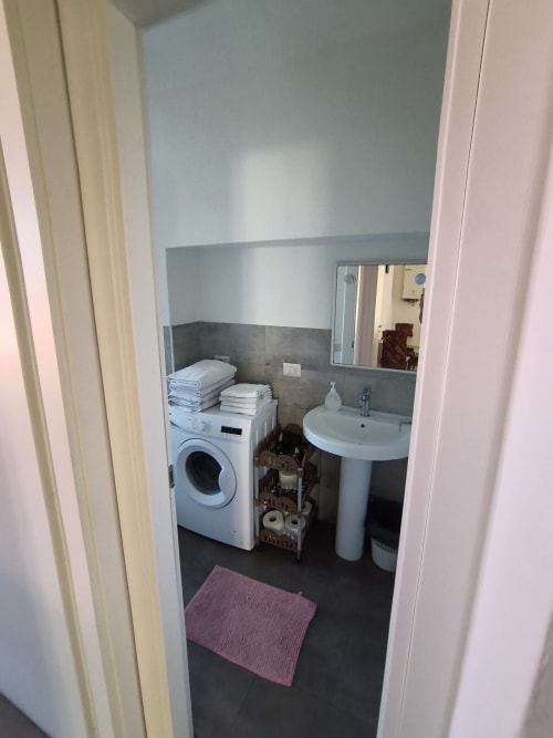 Modern bathroom with washing machine, pedestal sink, mirror, and storage at Casa di Alfredo in Siena