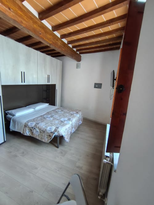 Modern bedroom in Casa di Alfredo apartment, Siena with wooden beams, bed, wardrobe, and wood flooring
