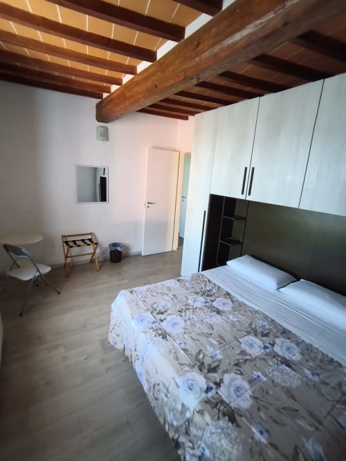 Spacious bedroom apartment at Casa di Alfredo in Siena with exposed wooden beams, twin beds, modern white cabinetry, and