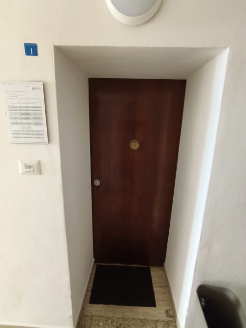 Apartment entrance at Casa di Alfredo in Siena with dark wooden door, white walls, and room number 1 sign