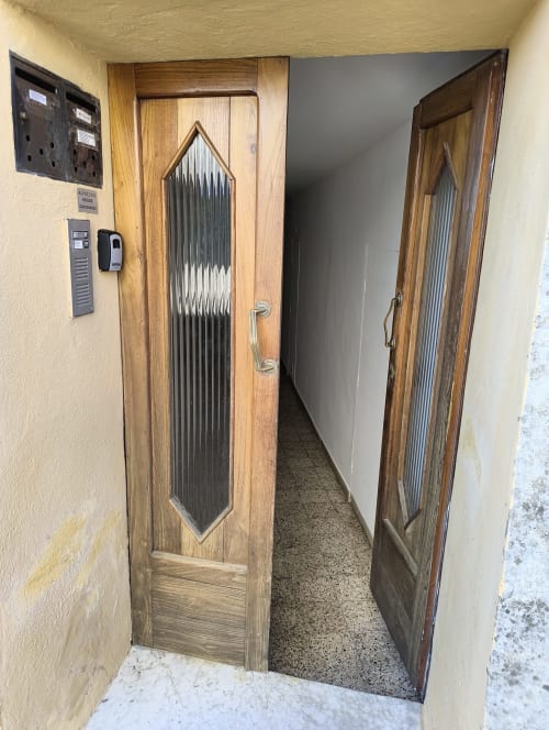 Wooden doors with frosted glass panels leading to hallway in Casa di Alfredo apartment, Siena