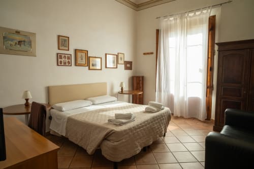 Camera luminosa presso Casa di Alfredo B&B a Siena con letto queen, testata color crema, mobili in legno e accesso al giardino
