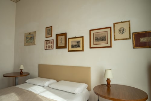 Camera elegante con letto matrimoniale, lampade comodino e quadri vintage sopra la testata a Casa di Alfredo B&B a Siena