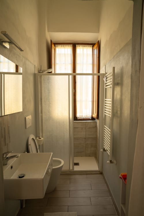 Bagno moderno di Casa di Alfredo B&B a Siena con doccia, lavabo, WC e finestra con accesso al giardino