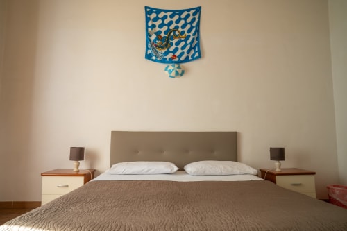 Camera da letto di Casa di Alfardo a Siena con letto matrimoniale, testata taupe, comodini e pannello decorativo blu alle pareti