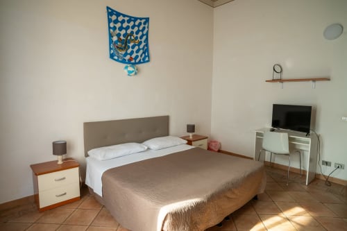 Camera da letto di Casa di Alfredo a Siena con letto matrimoniale, comodino, scrivania TV e arazzo blu