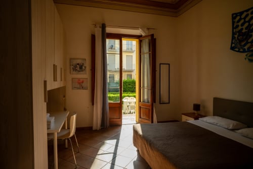 Camera luminosa di Casa di Alfredo B&B a Siena con letto matrimoniale, scrivania e portefinestre che si aprono sul giardino interno