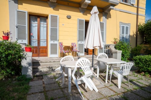 Terrazza soleggiata della Casa di Alfredo Siena B&B con arredamento bianco, ombrellone e facciata gialla