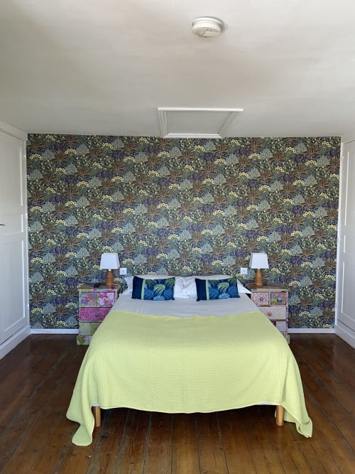 Modern bedroom at Abri Du Passant B&B in Roubaix with patterned wallpaper, lime bedcover, and wooden nightstands